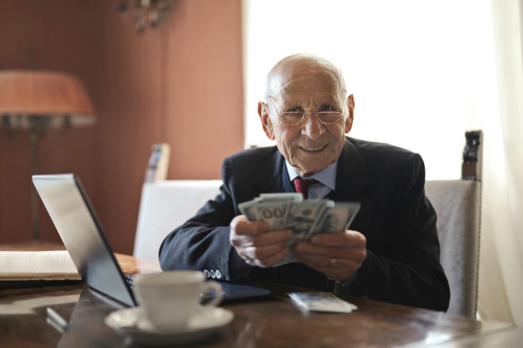 Senior couple reviewing Social Security retirement benefits on a laptop in the USA, smiling at financial planning documents.